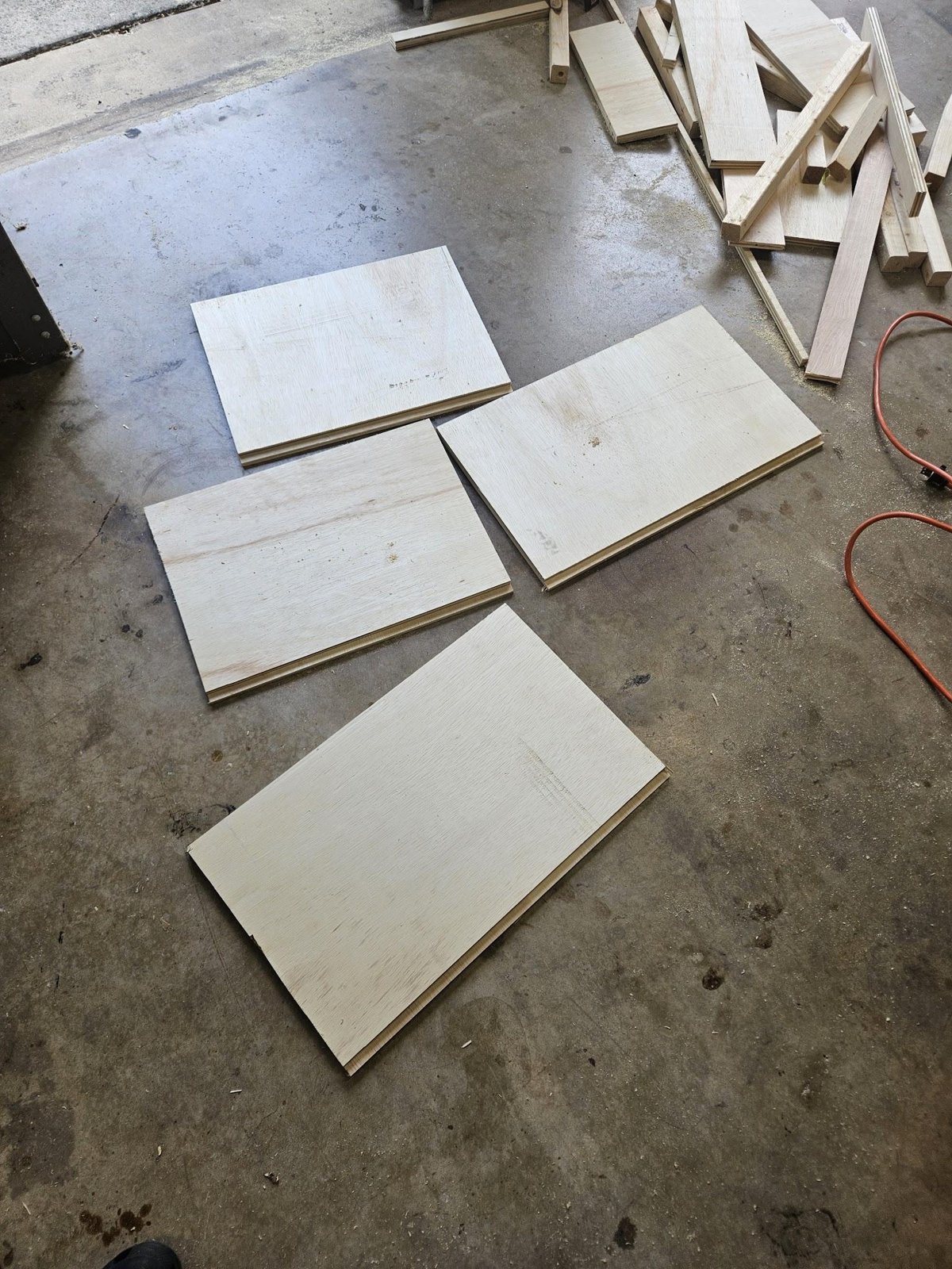 Four plywood drawer walls laid out flat on a garage floor