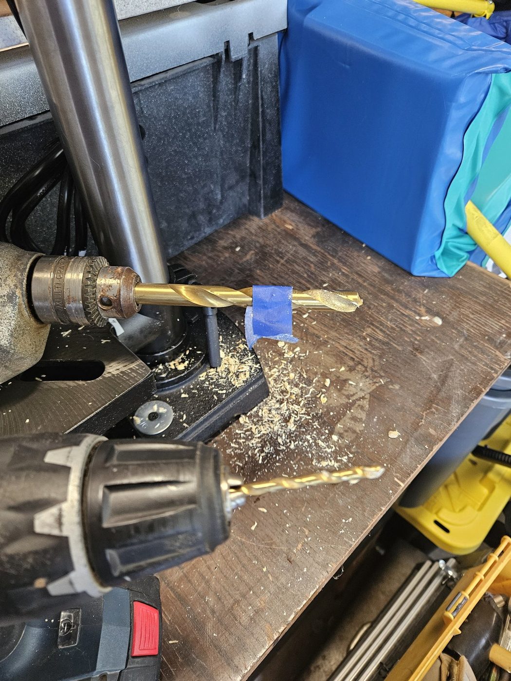 Two drills set up on the bench, one with a depth-of-cut tape flag on the bit, for boring the leg ends