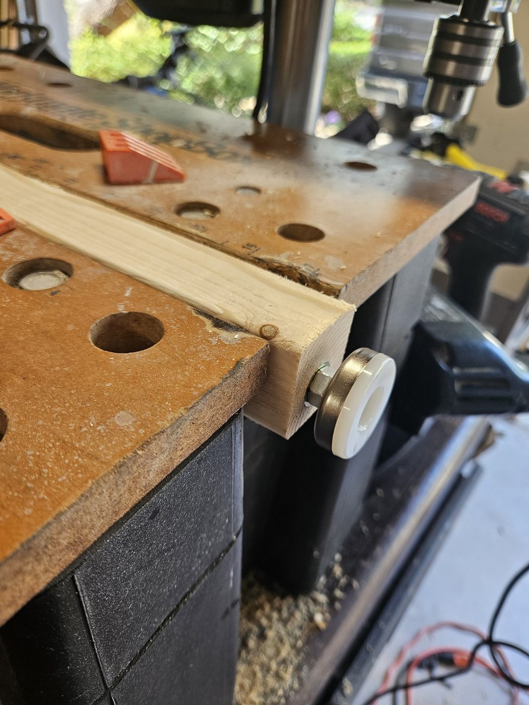 A leveling foot threaded fully home into the end of a wooden leg, showing the stud, hex collar and pad